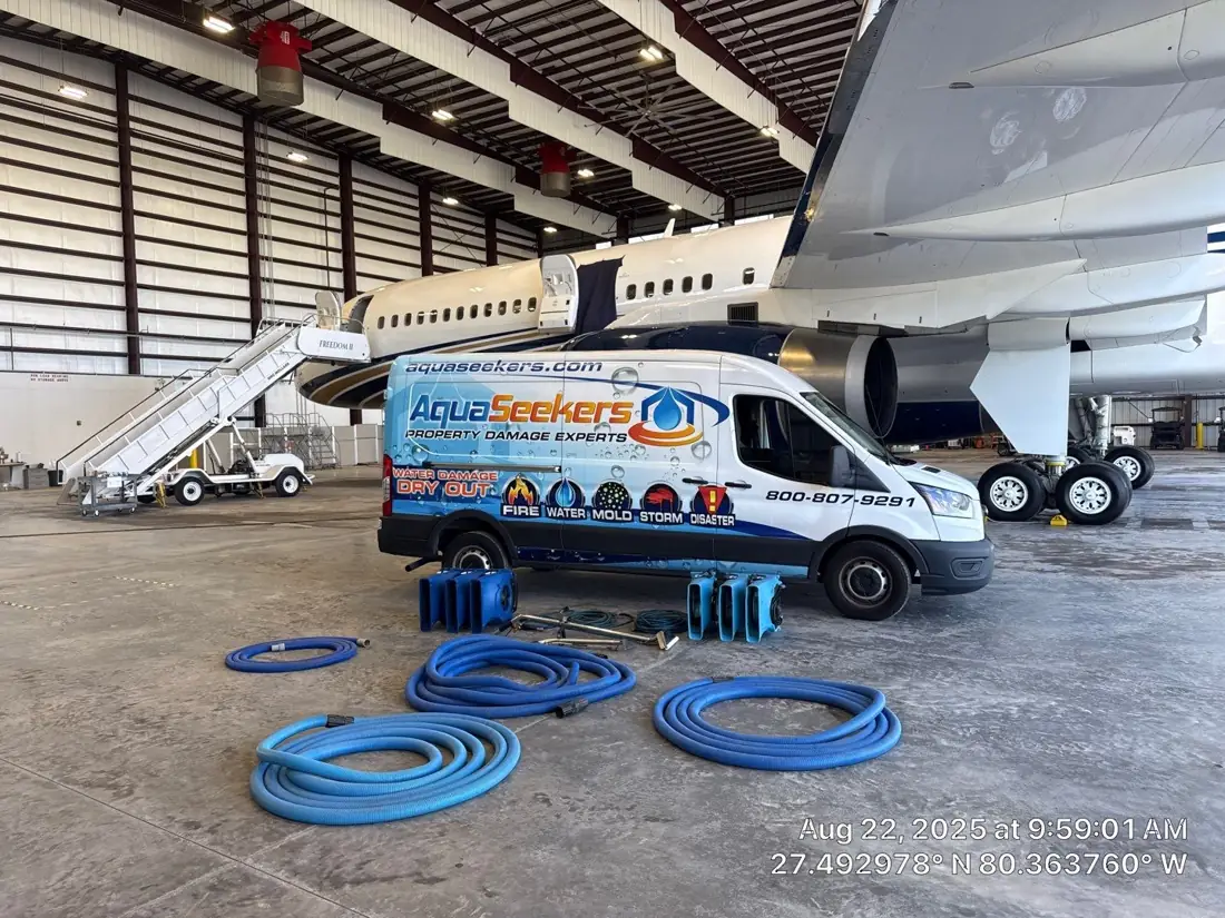 AquaSeekers van and restoration equipment beside an airplane in a hangar